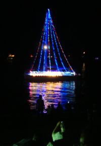 A sloop ablaze with Christmas lights.