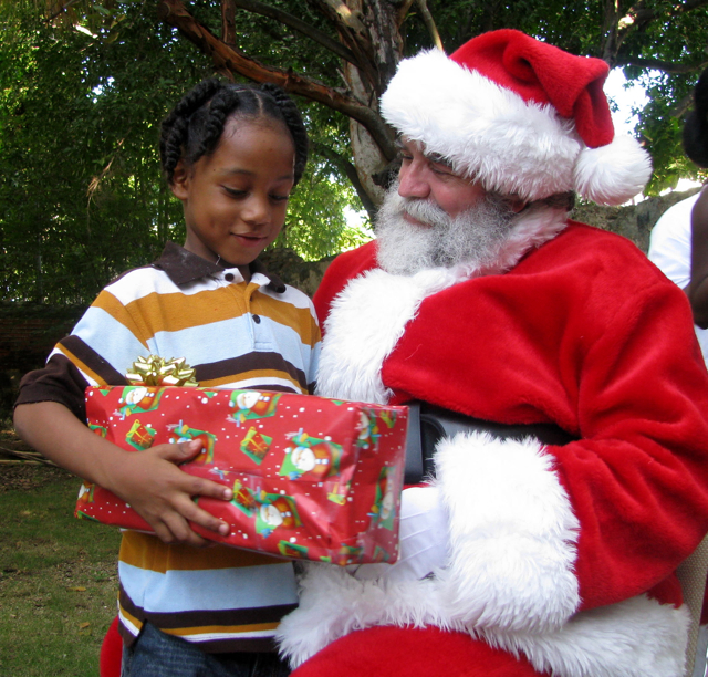 Santa Claus (Chris Finch) delivers a present to Santa delivered many smiles Sunday afternoon at Limpricht Park for the fourth annual Christmas In The Park.