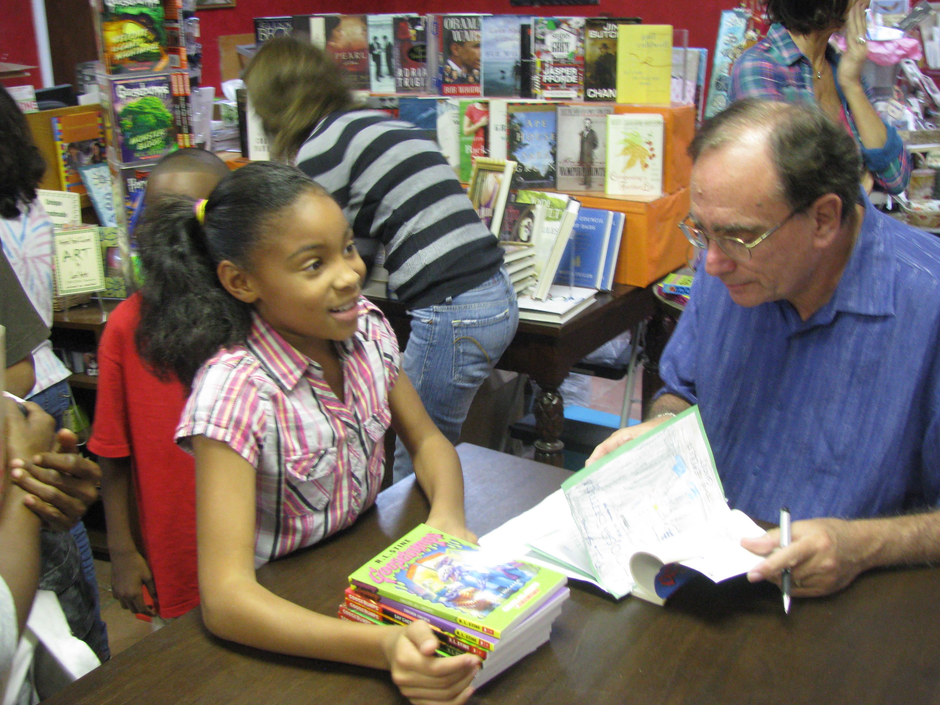R.L. Stine, author of the "Goosebumps" series for children, signs 9-year-old A'Jadah Mitchell's stack of books Wednesday evening at Undercover Books and Gifts.