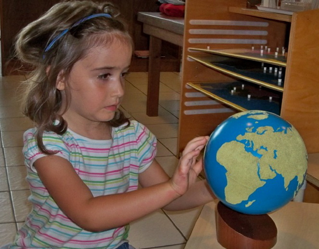 Emma Hawley feels land masses on a globeat the St. Croix Montessori School.