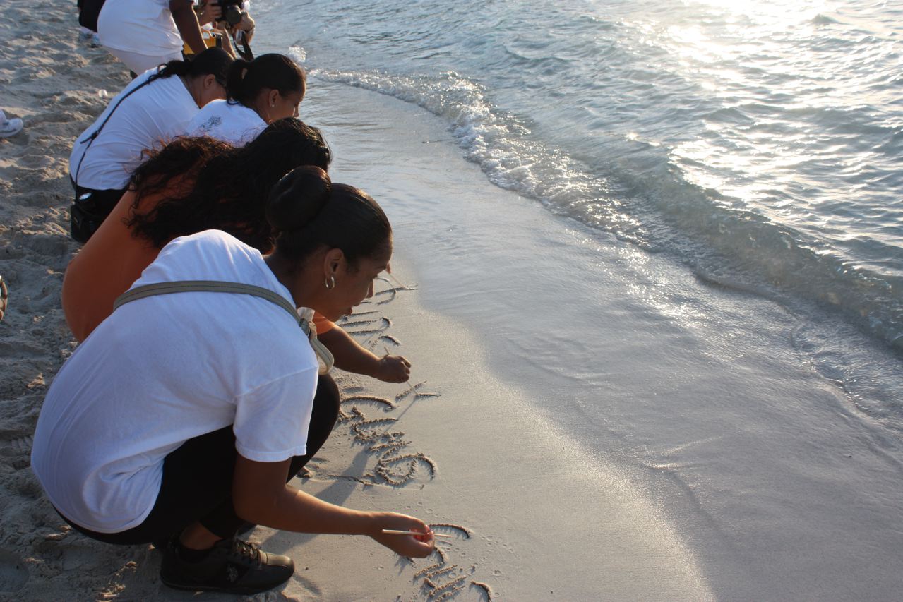 Peace walk participants write in the sand as part of a healing exercise.