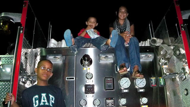 From left, Ronald Schjang, Jaydan Lezama and Amiah Shearm watch the fireworks from a firetruck.
