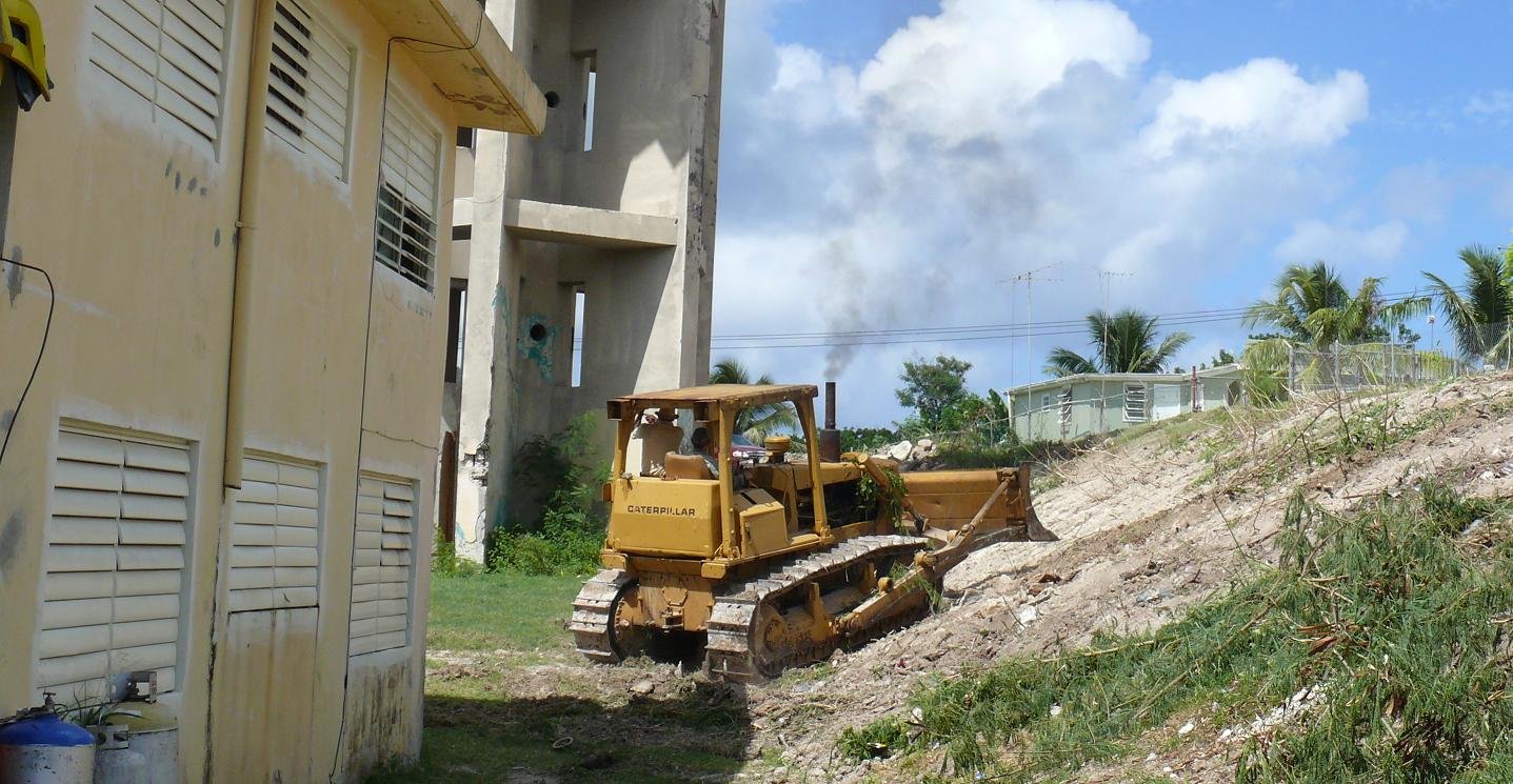 Public Works crews help the V.I.Police Department by bulldozing brush around Aureo Diaz Heights apartments Wednesday.