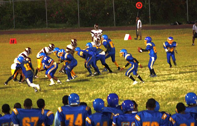 Charlotte Amalie High School, in blue, runs a play against a stubborn Eudora Kean defense.
