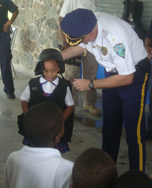 Deputy Chief Christopher Howell puts police gear on kindergartner Renisa Williams.
