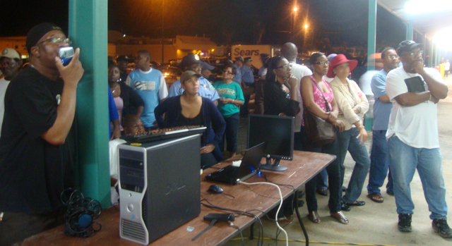 People gather around the front of the Elections Office to study returns from Saturday's Democratic primary, which were being projected onto the wall from a computer.