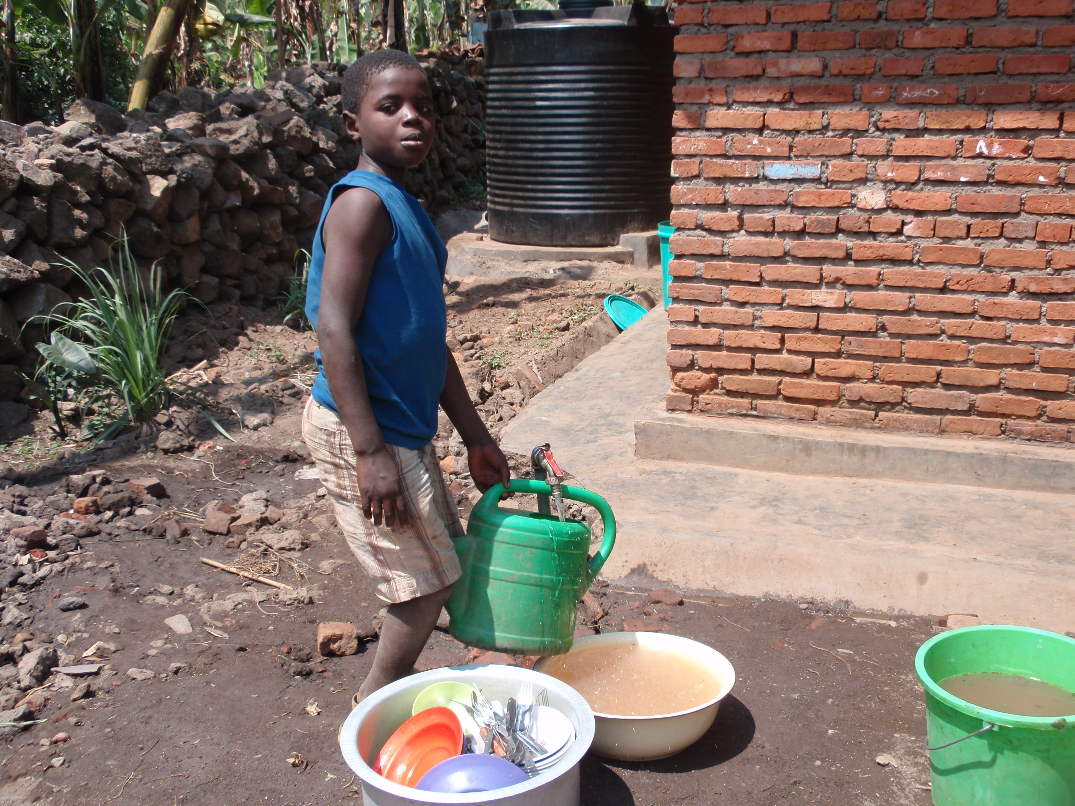 Village youngster fills watering can at newly installed water line.