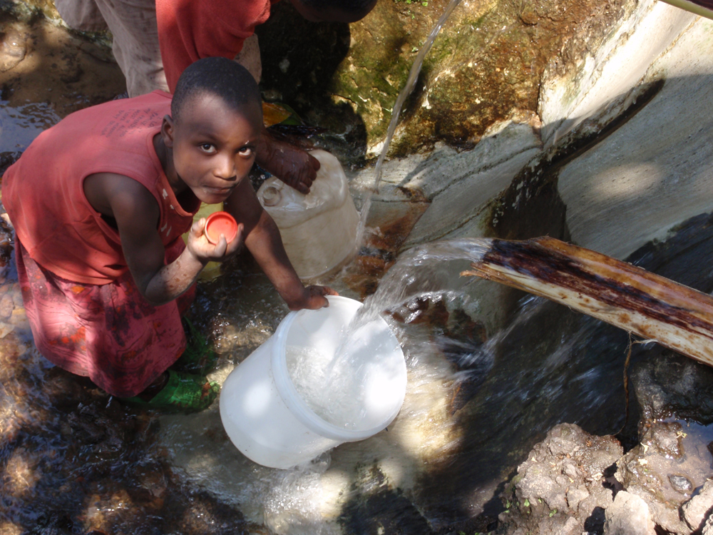 Village boy gets water the old-fashioned way after walking a long distance to the source.