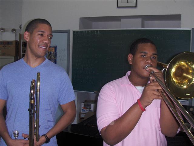 Renowned trombonist Weston Sprott (left) smiles appreciatively as student musician Juan Martinez plays.