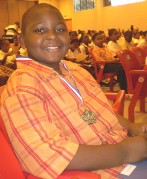 Almando Milligan beams with pride, his 'Shining Star' medal hanging from his neck.