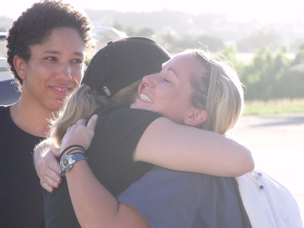 Dr. Sara Smith (left) looks on as Nurse Michelle Shiel (right) receives a welcome-home hug. 