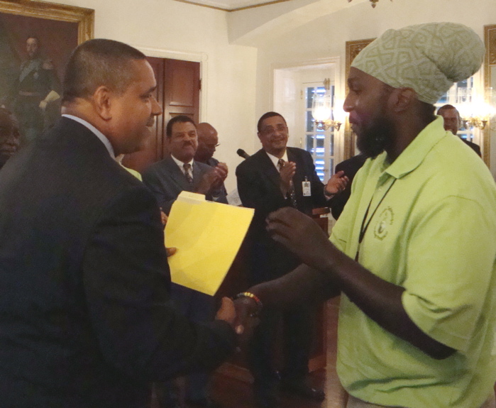 Kenneth Turnbull receives his certificate and congratulations from Gov. John deJongh Jr. Thursday at Government House.