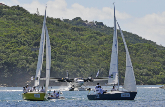 V.I.'s Team Island Sol, skippered by Nikki Barnes, (left) and Puerto Rico's Jorge Santiago sail ahead of a seaplane landing in St. Thomas harbor.