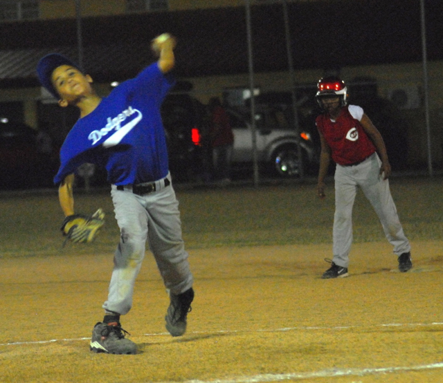 Dodgers’ closer Aldemar Santos fires a pitch to the plate while the Reds' Jahmonie Morton watches from second.