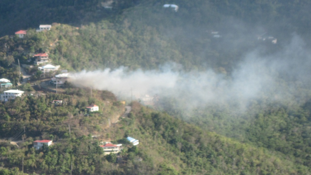 Smoke billows out of the Coral Bay home Monday afternoon, as seen from Ajax Peak.