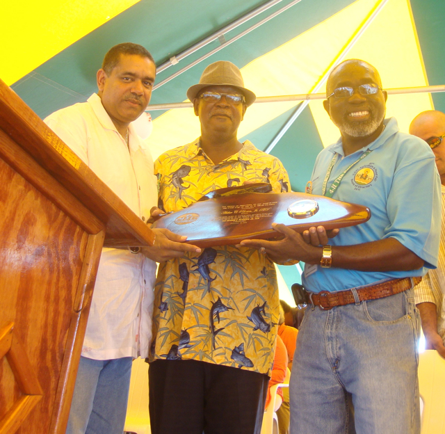 Gov. John deJongh Jr., left, and Kofi Boateng, right present a plaque commemorating Arthur C. Petersen's contribution to St. Croix Agriculture.