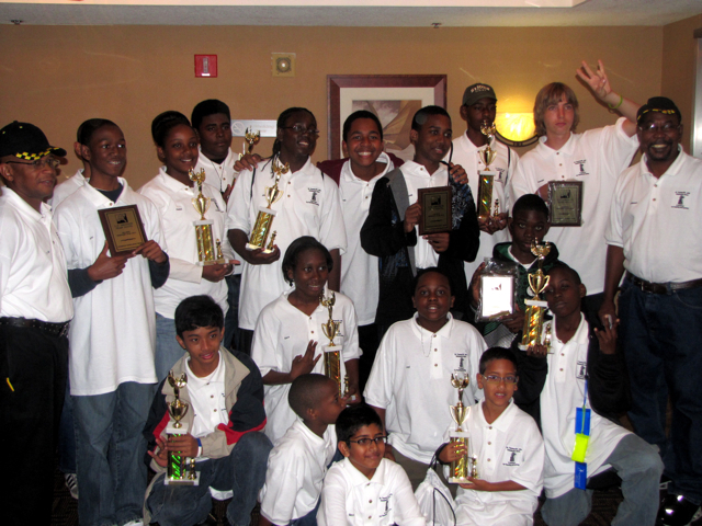 Young V.I. chess masters shown hoisting their hardware.