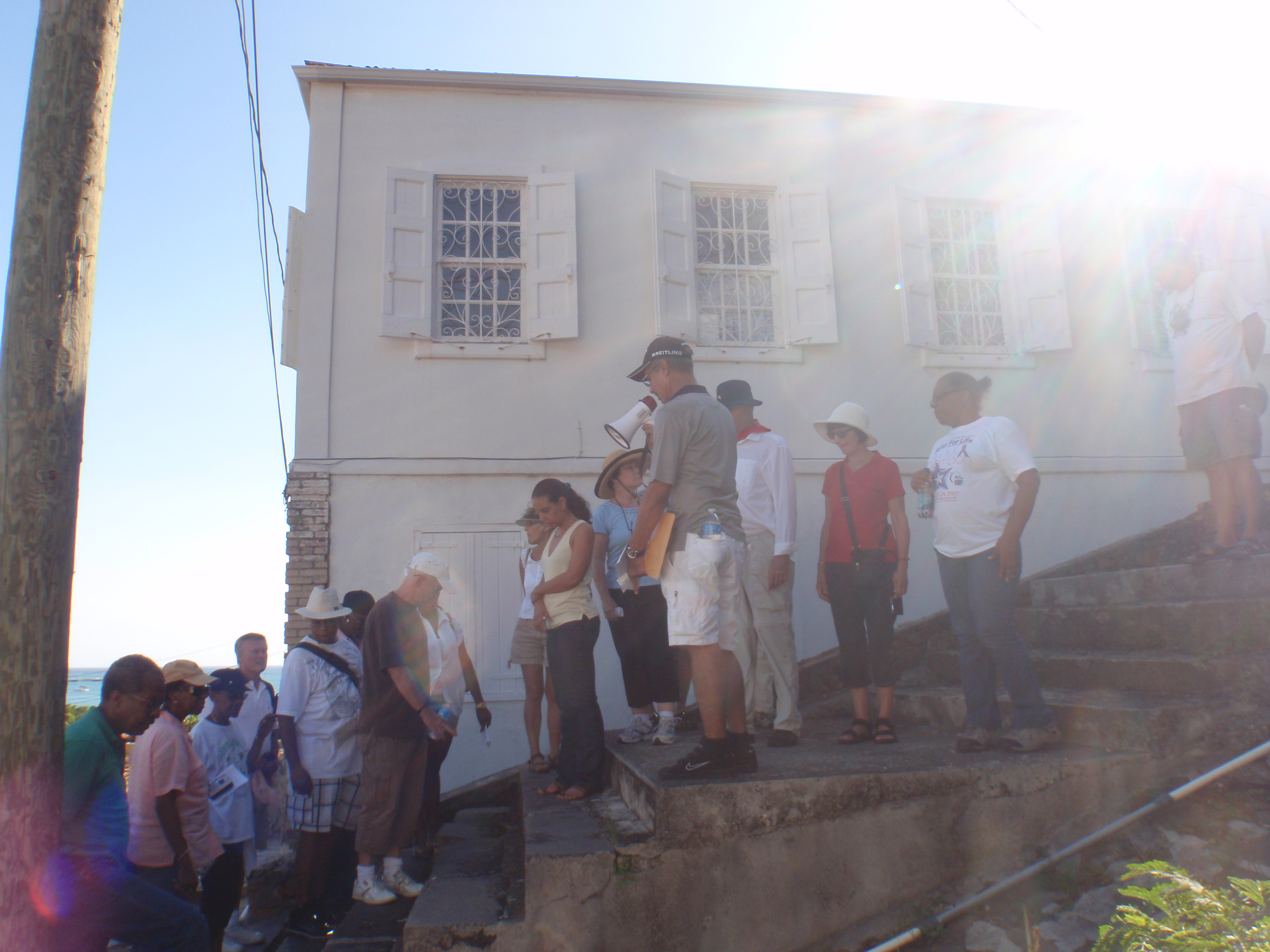 The sun emerges from behind a building as tour participants pause to hear about Charlotte Amalie's historic step streets.