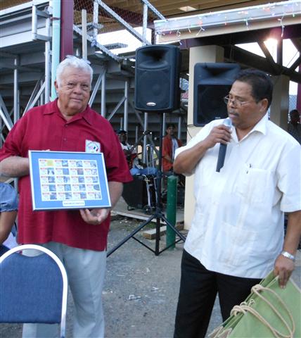 FTCO president Henry Richardson accepts plaque of V.I. Lottery July Frenchtown stamps.