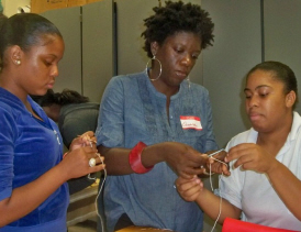 Oceana James (center) shows Xaise Aquino (left) and Sasha Morales how to make jewelry.