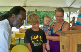 Errol Chichester (left) explains the workings of the hive to Anders Olson as his mom Karen Olson holds brother Osten.