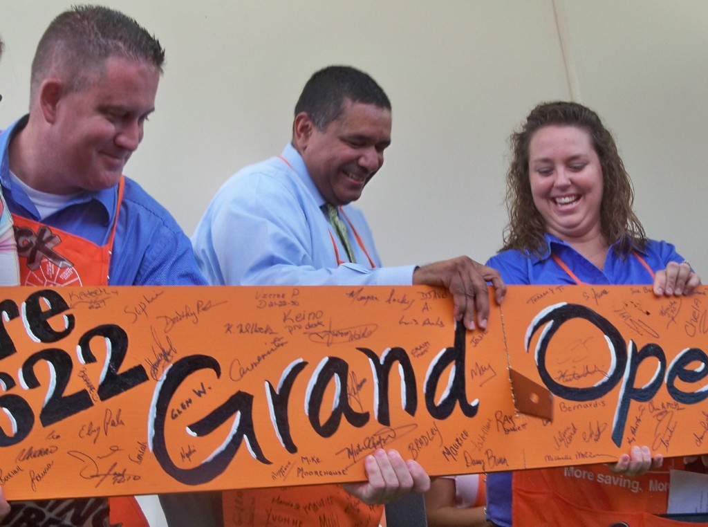 Gov. John deJongh Jr. (center) cuts the board with help from Home Depot empolyees, Chuck Kettle and Melissa Ward.