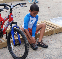 DeVonte Duncan, 9, puts his shoes on in preparation for biking.