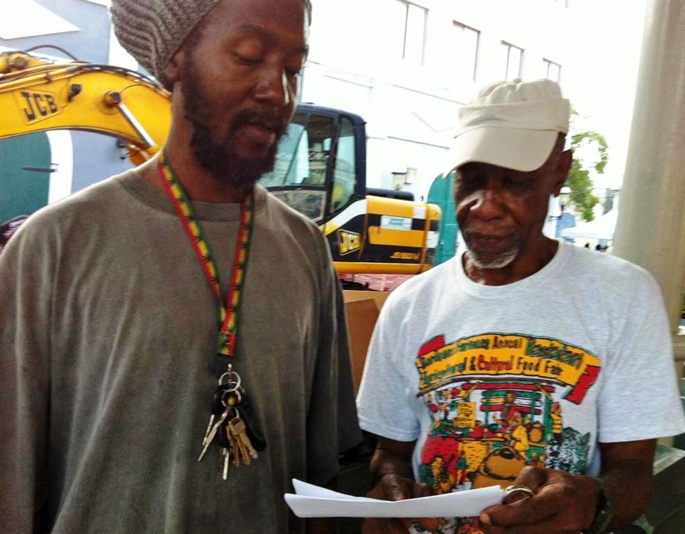 Farmers Earl "Zimba" Bedford, left, and Charlie Leonard look over the governor's statement at Saturday market (Molly Morris photo).