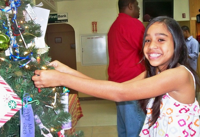 Twelve-year-old Kaylah Morales puts a mocko jumbie on the JFL Christmas tree (Carol Buchanan photo).