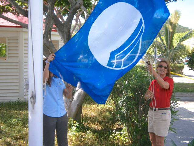 Marina operations manager Jane Wherren raises the Blue Flag at Crown Bay Marina Saturday.