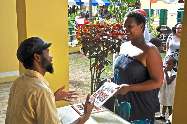 Moses Djeli, who created the images for "I Am the Virgin Islands," signs a copy at the sixth annual Governor's Christmas Party Saturday.