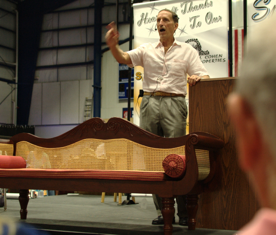 Auctioneer David Wilson with an antique mahogany and cane settee. 