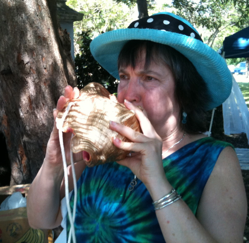 Carmen Doerge of Portland, Ore., blows a call on one of Junie Bomba's conch shell creations.