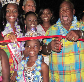 Clifton “Ashley” Boynes (right) cuts the ribbon opening Festival Village, aided by the royal court.