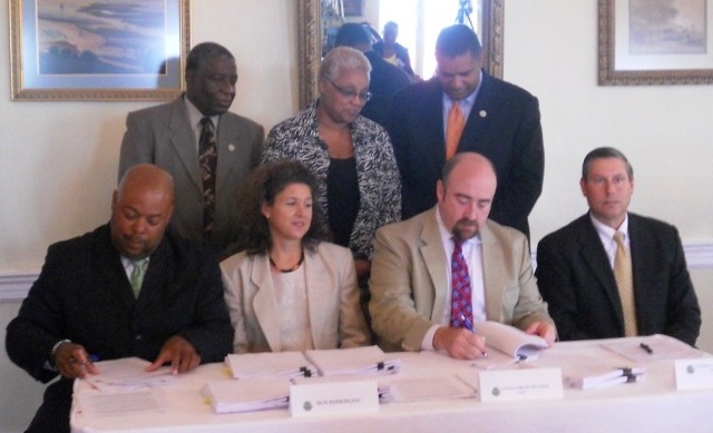 Local government and energy company officials sign documents establishing a partnership for WAPA to begin harnessing solar energy.