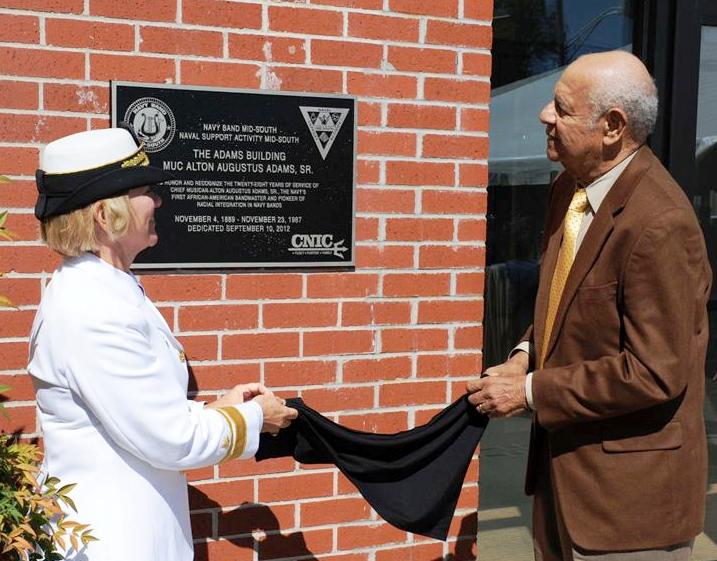 Rear Adm. Cindy Covell and Alton Adams Jr. unveil plaque naming a Navy band building for Alton Adams Sr.