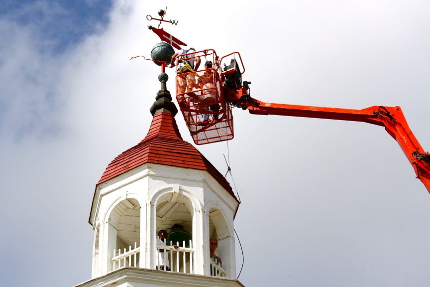 Joe Hollins and Richie Belliveau of Tip Top Construction return the historic weathervane to the top of the Steeple Building.