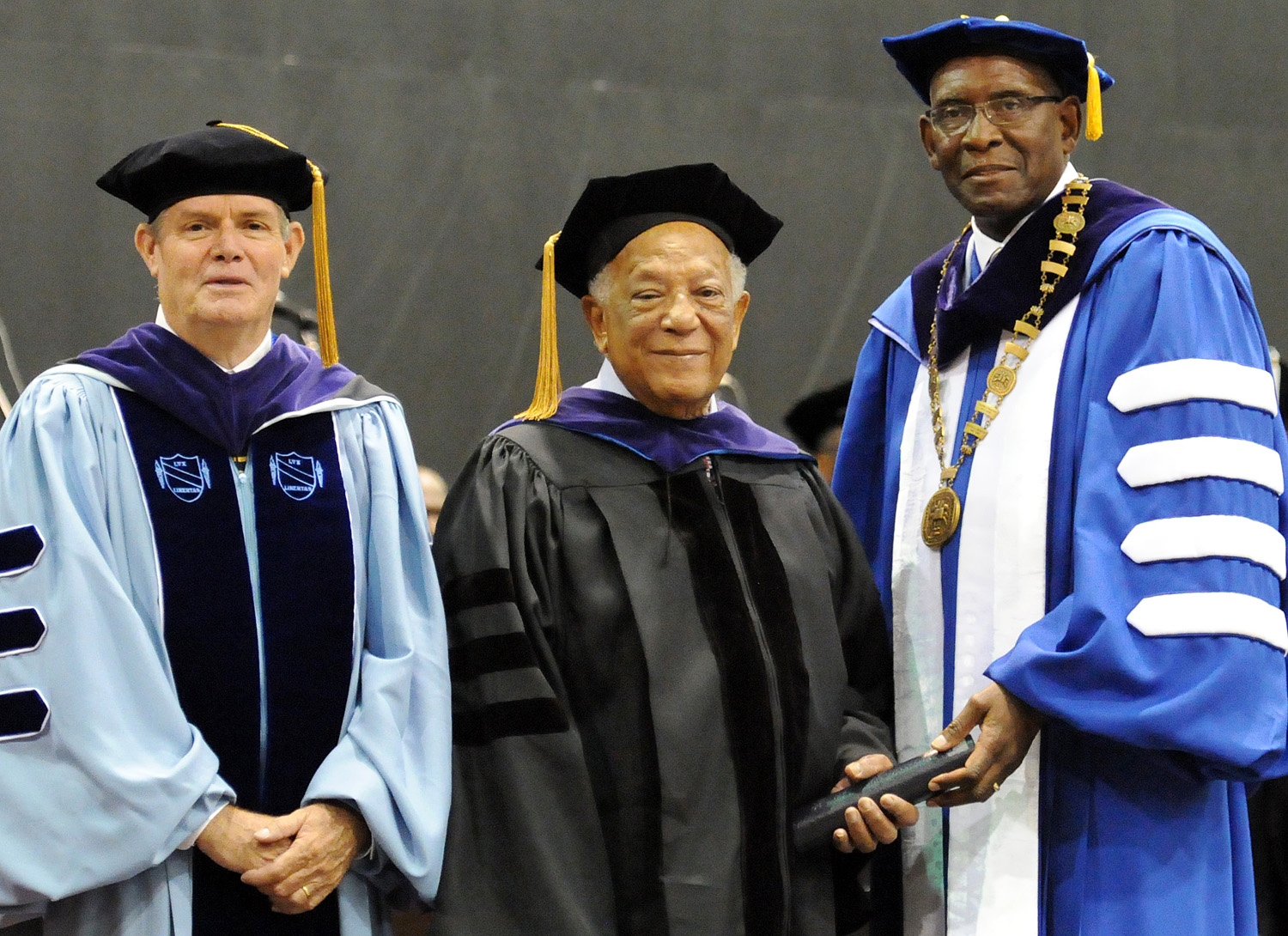 Ambassador Terence A. Todman, center, receives an Honorary Doctorate of Law degree during UVI 2013 Commencement  Ceremony from UVI President Dr. David Hall, right, and Attorney Henry C. Smock, who is now chair of the UVI Board of Trustees.