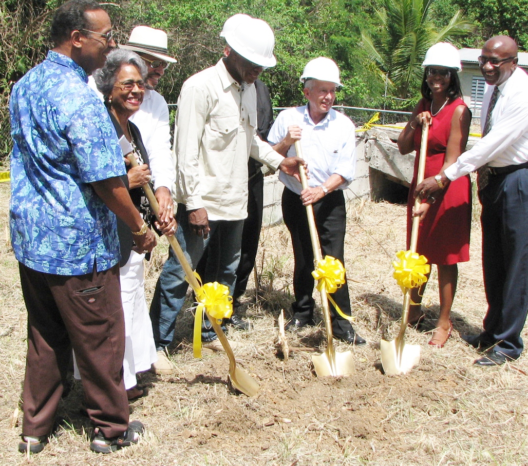 Pictured left to right: Rita Schuster and her two sons Troy and Gregory;  Benjamin Rogier of Bakah Construction; the Rev. Msgr. Michael Kosak in the background; Michael Akin, executive director of Catholic Charities; Adrienne L. Williams, executive director, V.I. Housing Authority and St. Croix Administrator Dodson James.