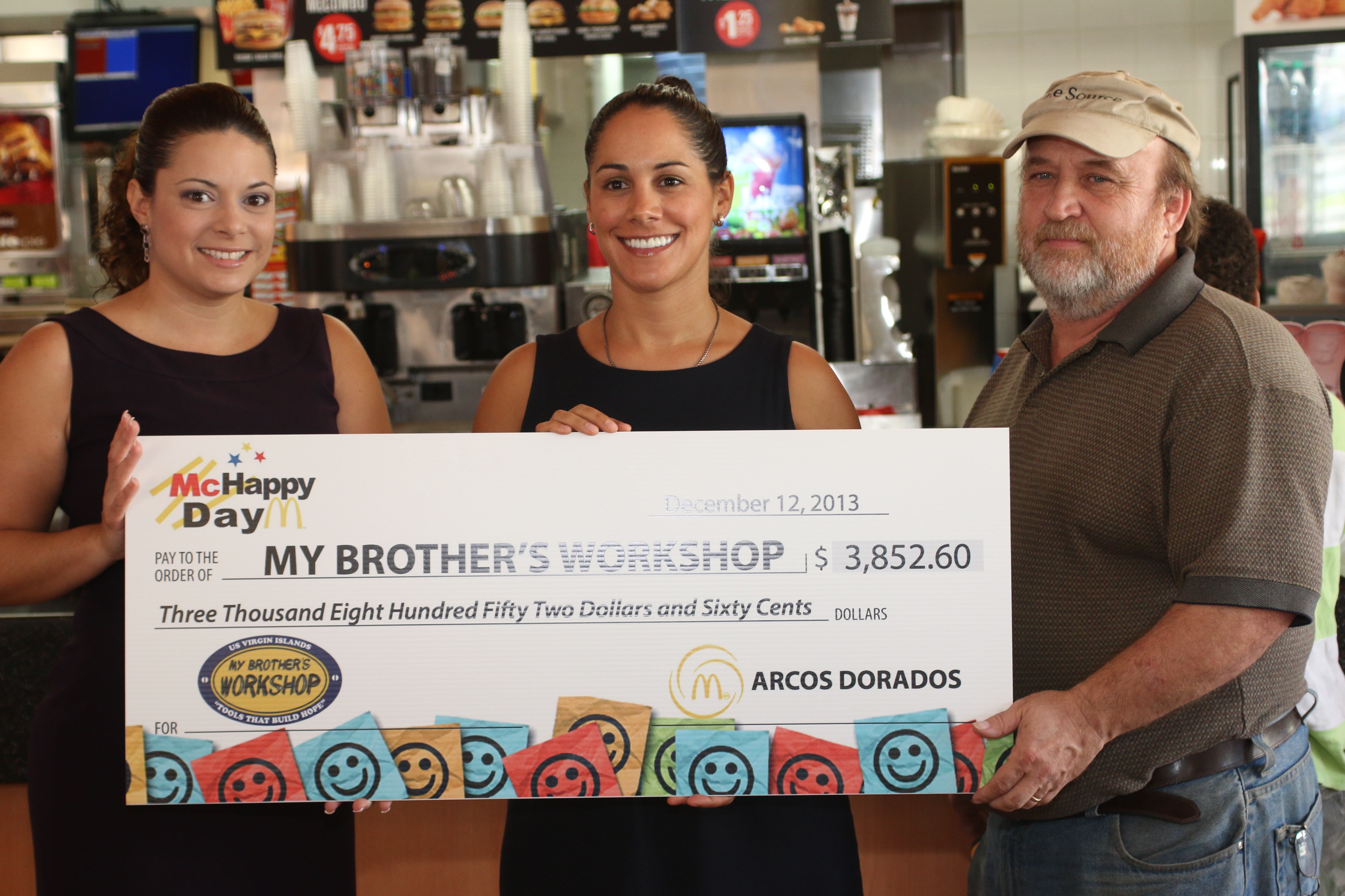 Photo: Mildre Quiles (left) presents Christina Luton and Scott Bradley of My Brother's Workshop with a check from McDonald's for the proceeds raised through the 2013 McHappy Day Campaign.