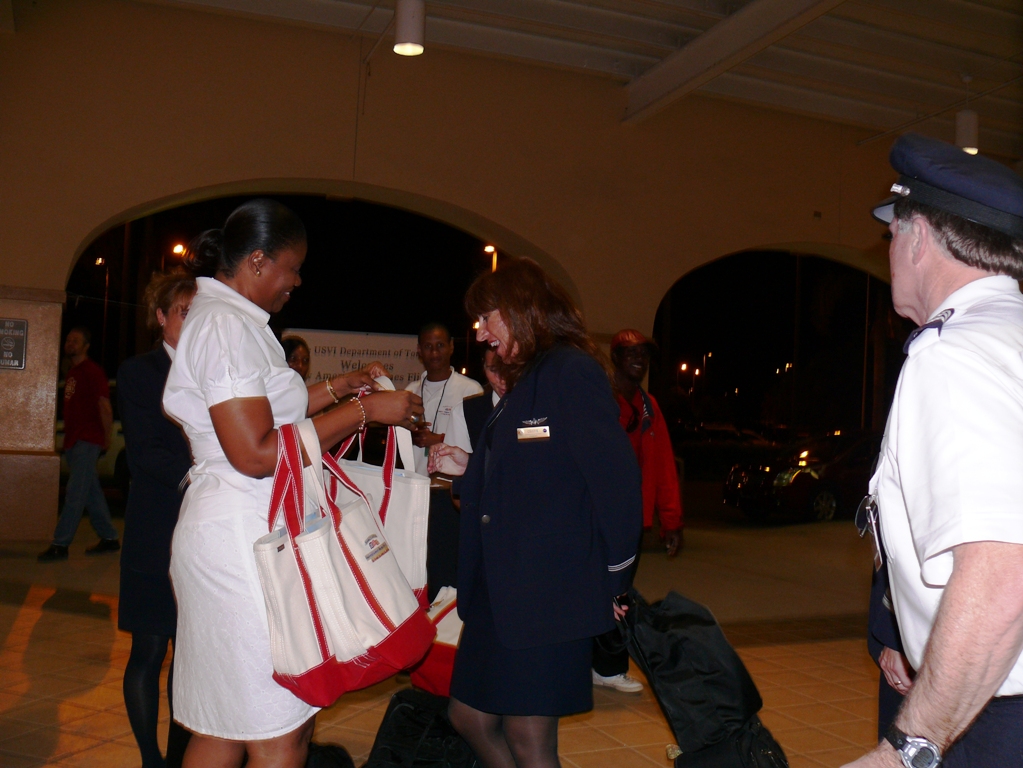 Tourism officials welcome passengers and crew from American Airlines flight No. 879 with warm smiles and bags of goodies.