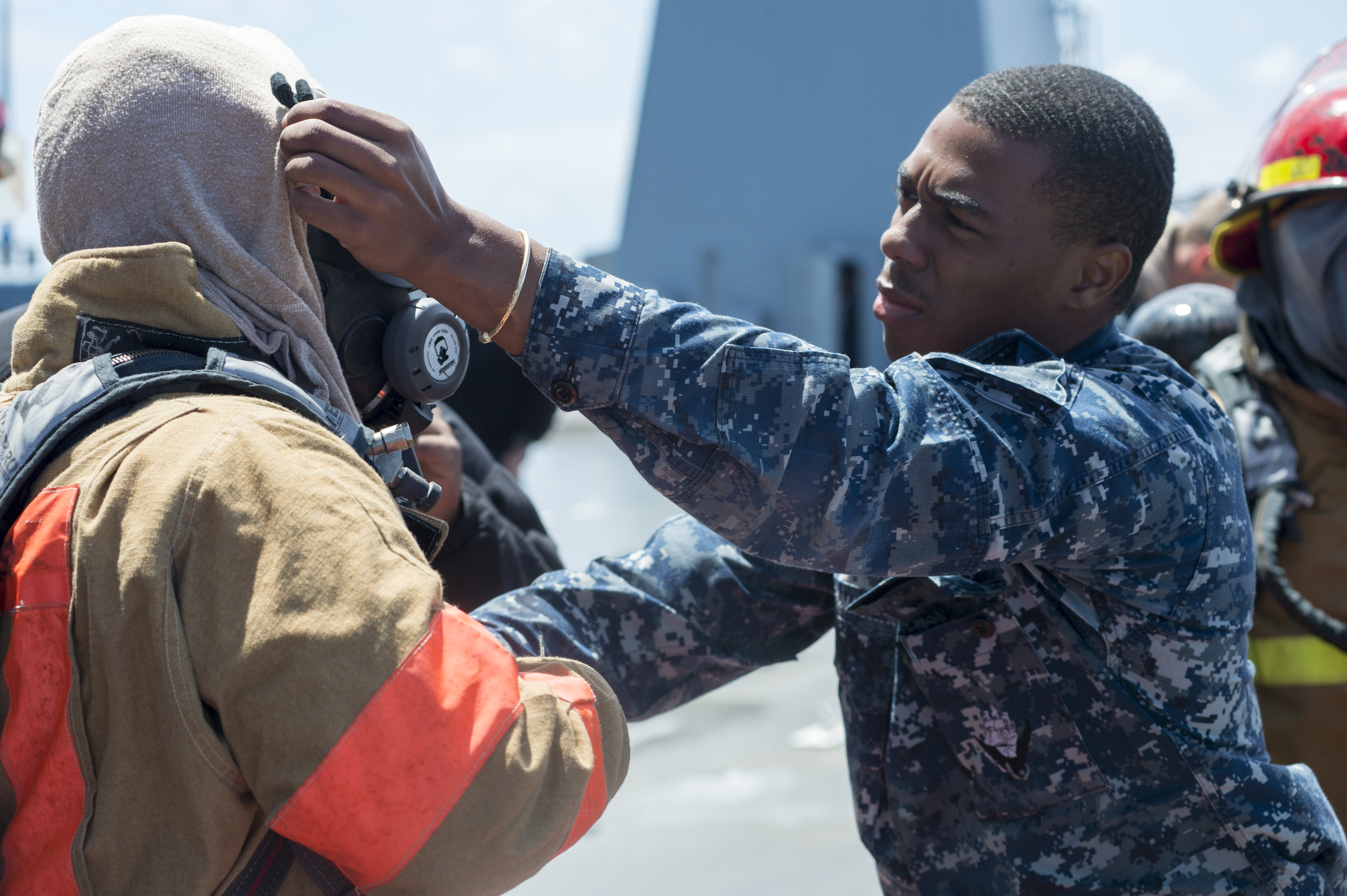 Baltic Sea Electronic Technician 3rd Class Sigui M. Howard-Magras, assigned to U.S. 6th Fleet command and control ship USS Mount Whitney (LCC20), helps out a sailor with putting on his face mask during a damage control exercise aboard the Mount Whitney. (photo by Mass Communication Specialist 3rd Class Luis R. Chavez Jr./released)