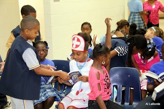 James Nosty, president of the  Rotary EarlyAct  Club of St. Thomas II, and a 6th grader  help  a 3rd grader dressed  as a nurse for Halloween to find the word as  students in the row behind assist  each other to use the new dictionary. (Photo by Rotarian Alphonso LaBorde)