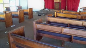 Broken glass and trash litter the floor of the chapel.