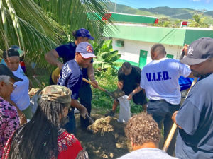 Residents gather at the Tutu fire station Monday morning for sandbag distribution.