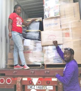 Sen. Janelle Sarauw joins Vernon Araujo in off-loading and distributing supplies to residents.