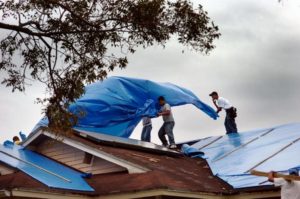 Operation Blue Roof workers install tarps on storm-damaged homes in the territory. (Source file photo)