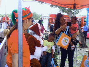 Santa gives toys and books to children at the Coquito Festival Saturday. 