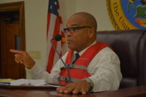 Sen. Brian Smith (D-STT) wears a life vest while chairing Friday's Homeland Security, Justice and Public Safety Committee hearing, in a gibe at VITEMA's late tsunami alert. (Photo by Barry Leerdam, provided by the V.I. Legislature)