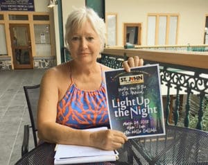 Mary Bartolucci displays a poster for the March 24 event.